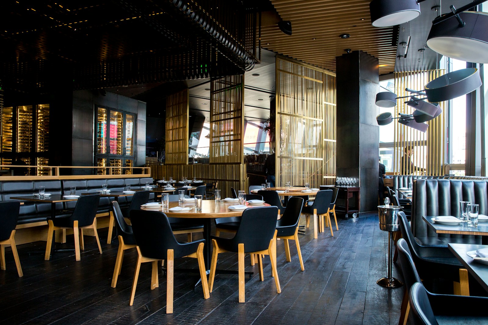 Salle de restaurant habillée de boiseries sombres, comptoir en frêne olivier